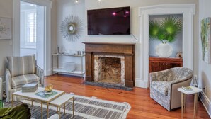 A living room with a fireplace, a television mounted above it, and a decorative mirror.