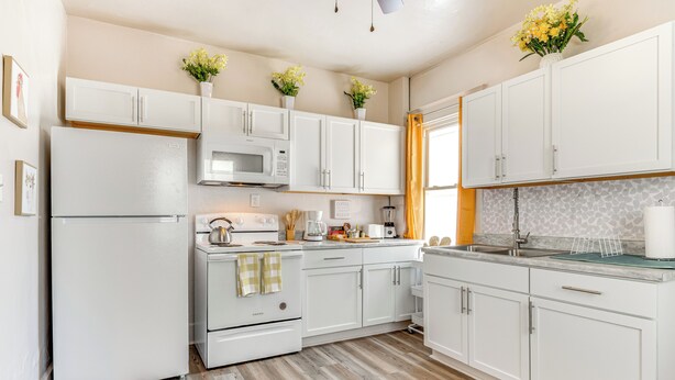 A modern kitchen with white cabinetry, a microwave, a stove, and a sink. - 3 Mi to Dtwn Indy: Pet-friendly Home w/ Backyard! (Indianapolis)