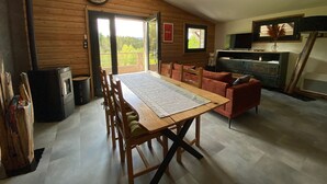 A cozy cabin interior with a wooden dining table, chairs, a fireplace, and a television. - Renovated chalet with sauna, near Gérardmer (Sapois)