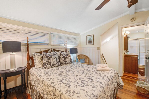 A bedroom with a bed, bedside table, lamp, and a chair. - Seabrook Exclusives | 527 Tarpon Pond (Seabrook Island)