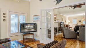 A living room with a television, wicker furniture, a glass coffee table, and a fireplace.