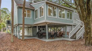 A two-story house with a covered patio area, a staircase, and a barbecue grill.
