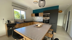 Eine moderne Küche mit einer großen Kochinsel, Holzschränken und Blick ins Freie.