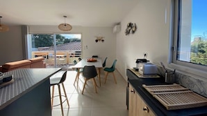 Eine moderne Küche mit Essbereich, großen Fenstern und Blick ins Freie.