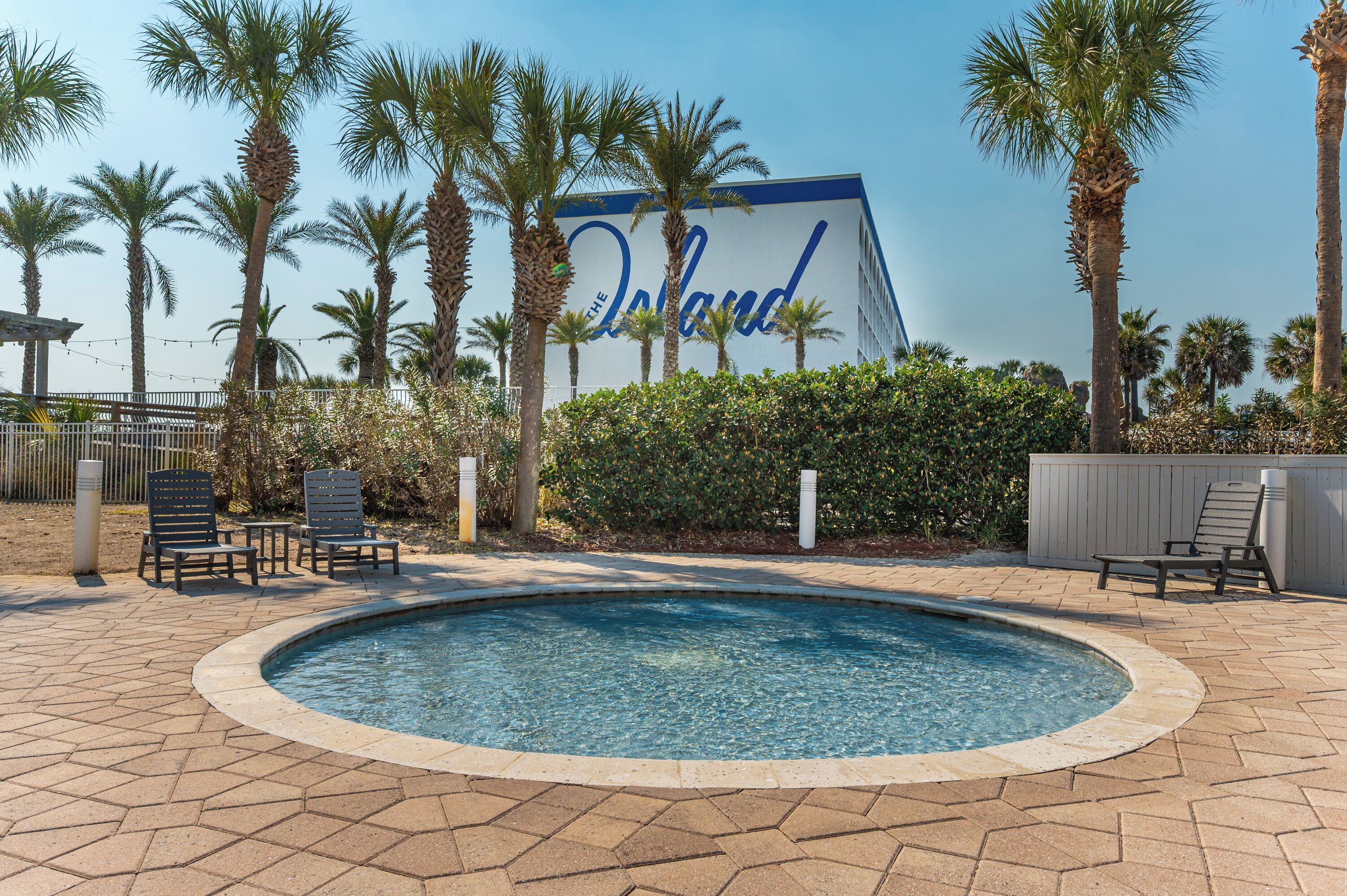 A swimming pool area with lounge chairs and palm trees.