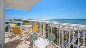 A balcony with a view of the ocean, yellow chairs, and a table. - G501 Corner 2BR + Bunk w/ Gulf Views, Balcony & Free Beach Service (Fort Walton Beach)