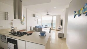 Una cucina moderna con isola centrale, zona pranzo con vista e soggiorno con televisore e opere d'arte.