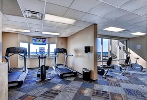 Une salle de sport d’hôtel équipée de tapis de course, d’appareils elliptiques et de vélos d’exercice.