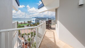 A balcony with a view of the beach and a hotel building in the background. - G616 Tropical oasis with wraparound balcony, Gulf views & top-tier amenities! (Fort Walton Beach)
