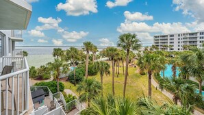 A resort with a pool, palm trees, and a view of the ocean. - Heron 406 | Bay & Lazy River Views | Spacious 3BR Retreat w/ Balcony! (Ft. Walton Beach)
