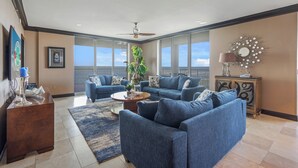 A spacious living room with two blue sofas, a coffee table, and a large plant. - HPH03 Luxury Bayfront Penthouse | Rooftop Hot Tub | Stunning Views! (Fort Walton Beach)