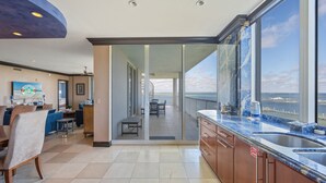 A modern kitchen with a large window overlooking the sea, a dining area with a view, and a spacious living room with a large TV. - HPH03 Luxury Bayfront Penthouse | Rooftop Hot Tub | Stunning Views! (Fort Walton Beach)
