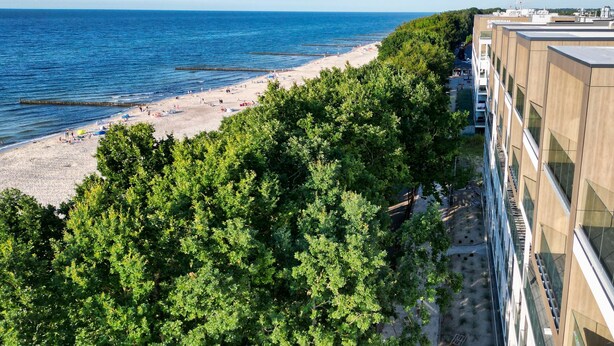 A beach with a clear view of the sea and a building with a modern design. - RentPlanet - Perłowa Przystań (Sianożęty)
