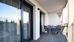 A balcony with a table and chairs, large windows, and a view of the city. - RentPlanet - Perłowa Przystań (Sianożęty)