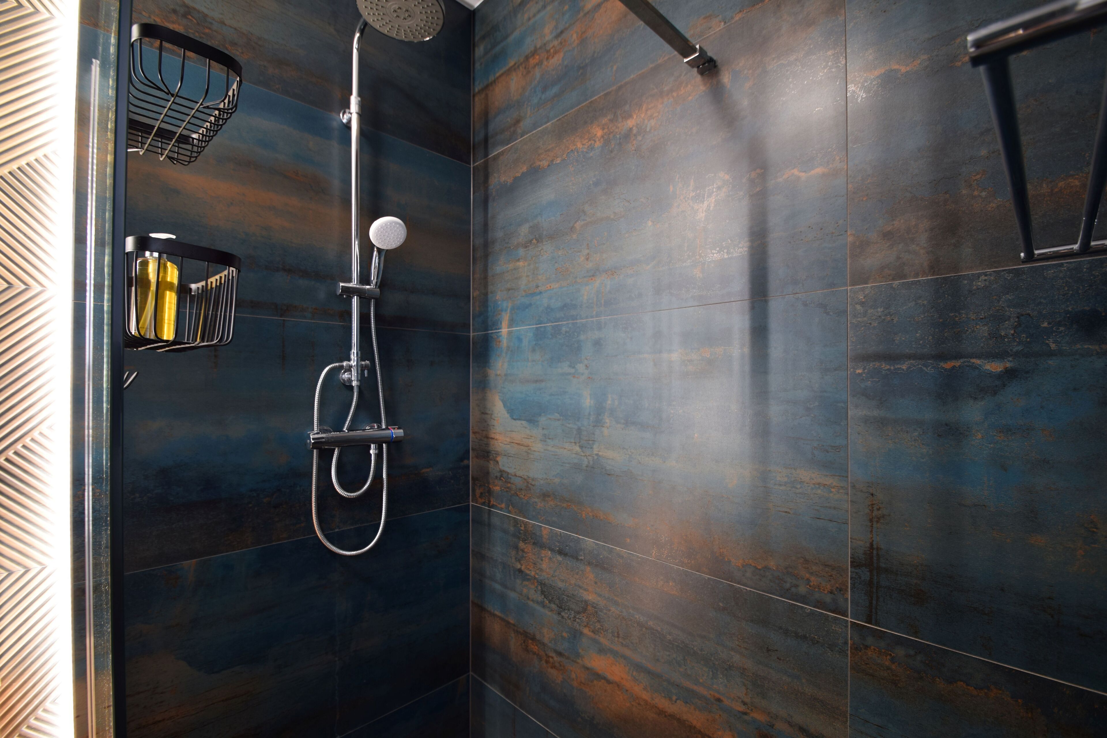 Una ducha moderna con cabezal de ducha de mano y llave de pared.