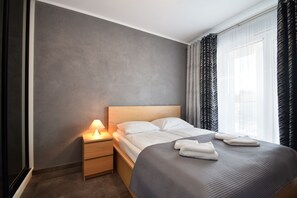 Relax in a serene space with a neatly made bed, a nightstand, and ambient lighting.