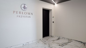 A modern hallway with a marble floor and a sign reading "PERŁOWA PRZYSTAN". - RentPlanet - Perłowa Przystań (Sianożęty)