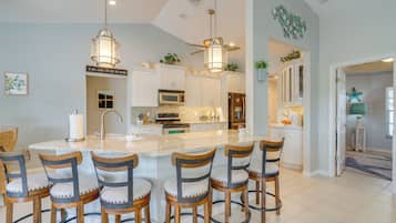 Uma cozinha moderna com ilha central, banquetas e iluminação pendente.