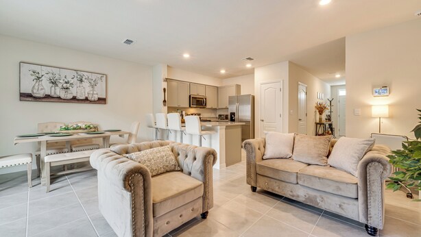 A modern living room with two beige sofas, a dining table, and a kitchen in the background. - Davenport Home w/ Pool Access & Patio! (Davenport)