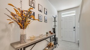 A hallway with a wooden console table, a vase with dried plants, and a coat rack. - Davenport Home w/ Pool Access & Patio! (Davenport)
