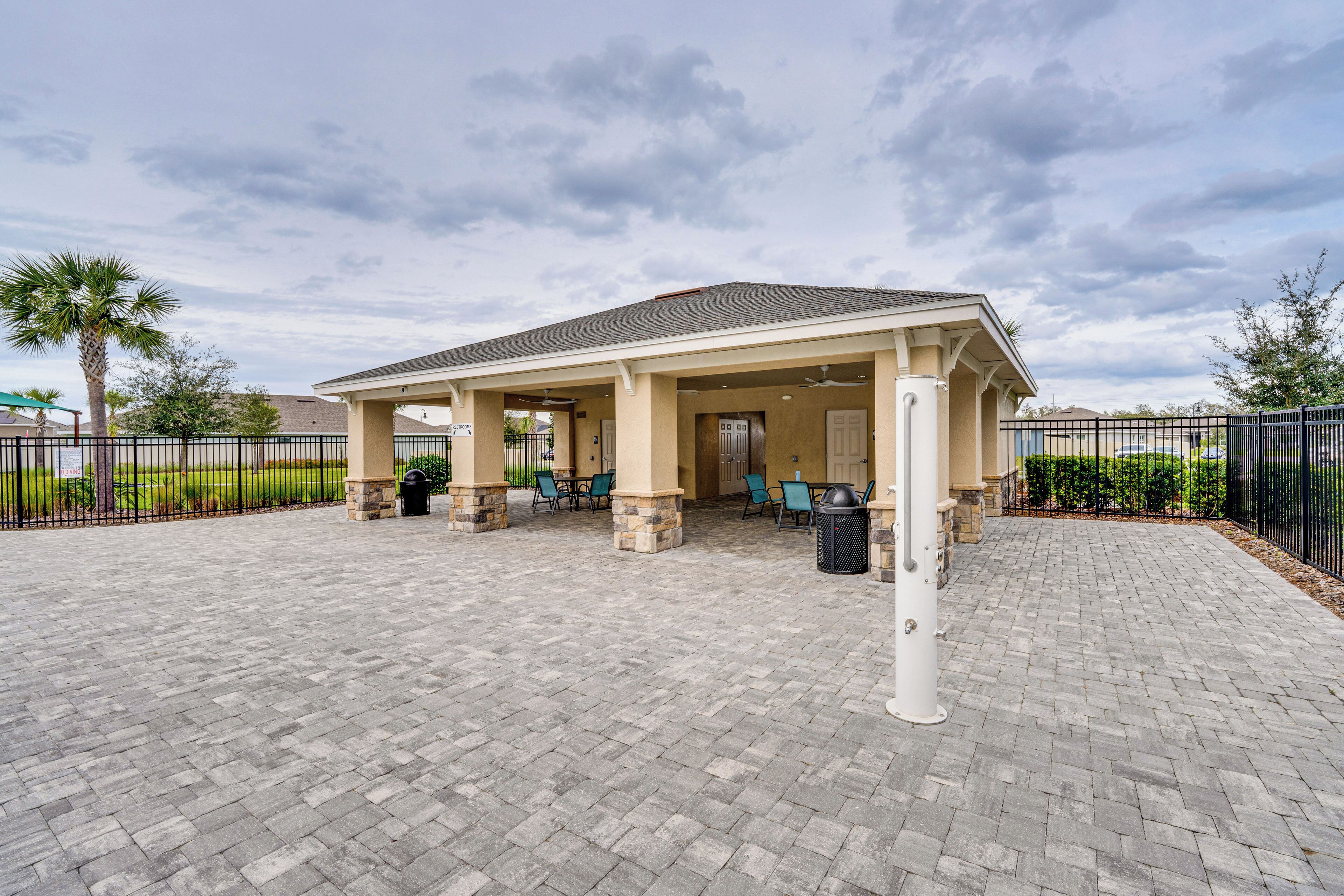 A covered patio area with stone pillars, outdoor seating, and a trash can.