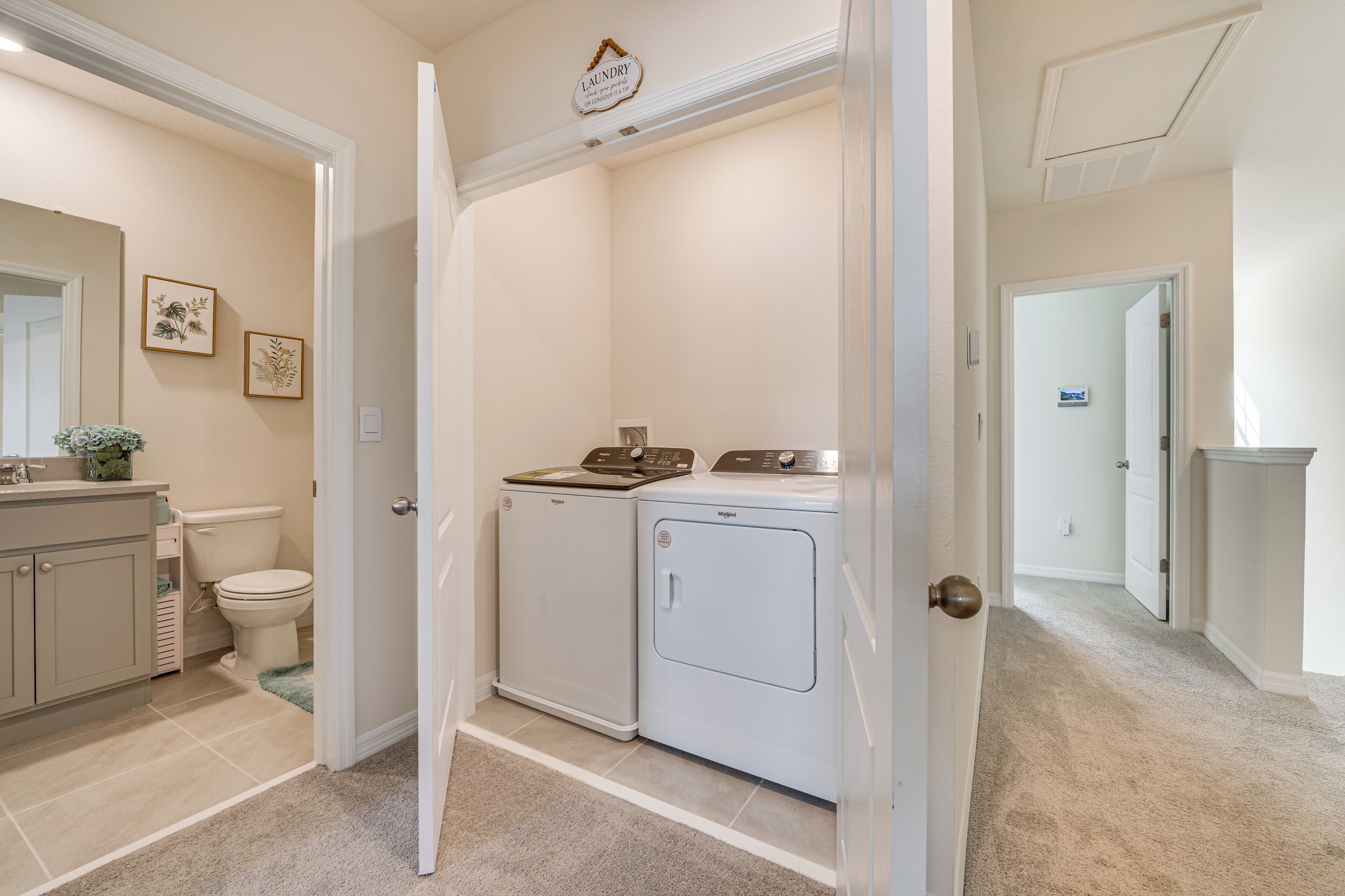 A laundry room with a washing machine and dryer, a toilet, and a sink with a mirror.