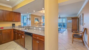 A modern kitchen with wooden cabinets, granite countertops, and a dishwasher. - O603 Spacious Bayside Condo | Panoramic Views | Lazy River & Resort Access (Fort Walton Beach)