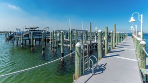 A pier with boats docked, wooden posts, and a walkway with railings. - Pelican 304 | 1BR Condo w/ Bunks | Lazy River Views & Resort Amenities (Fort Walton Beach)