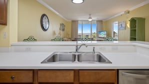 A kitchen with a double sink, wooden cabinets, and a clock on the wall.