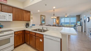 A modern kitchen with wooden cabinets, a white countertop, and a dishwasher. - P503 Romantic High-Floor 2BR Condo | Bay & Lazy River Views | Private Balcony (Fort Walton Beach)