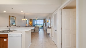 A modern kitchen with a dishwasher, a dining area with a view, and a door leading to another room. - P503 Romantic High-Floor 2BR Condo | Bay & Lazy River Views | Private Balcony (Fort Walton Beach)