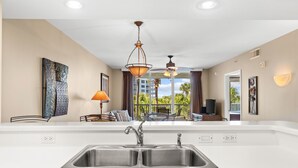 Una cocina moderna con una isla grande, pileta de acero inoxidable e iluminación colgante.