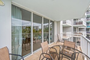 Un balcon avec une porte vitrée, des chaises en osier et une table.