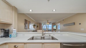 A modern kitchen with a large island, stainless steel appliances, and a view of the outdoors. - S506 Destin West Sandpiper #506 (Fort Walton Beach)