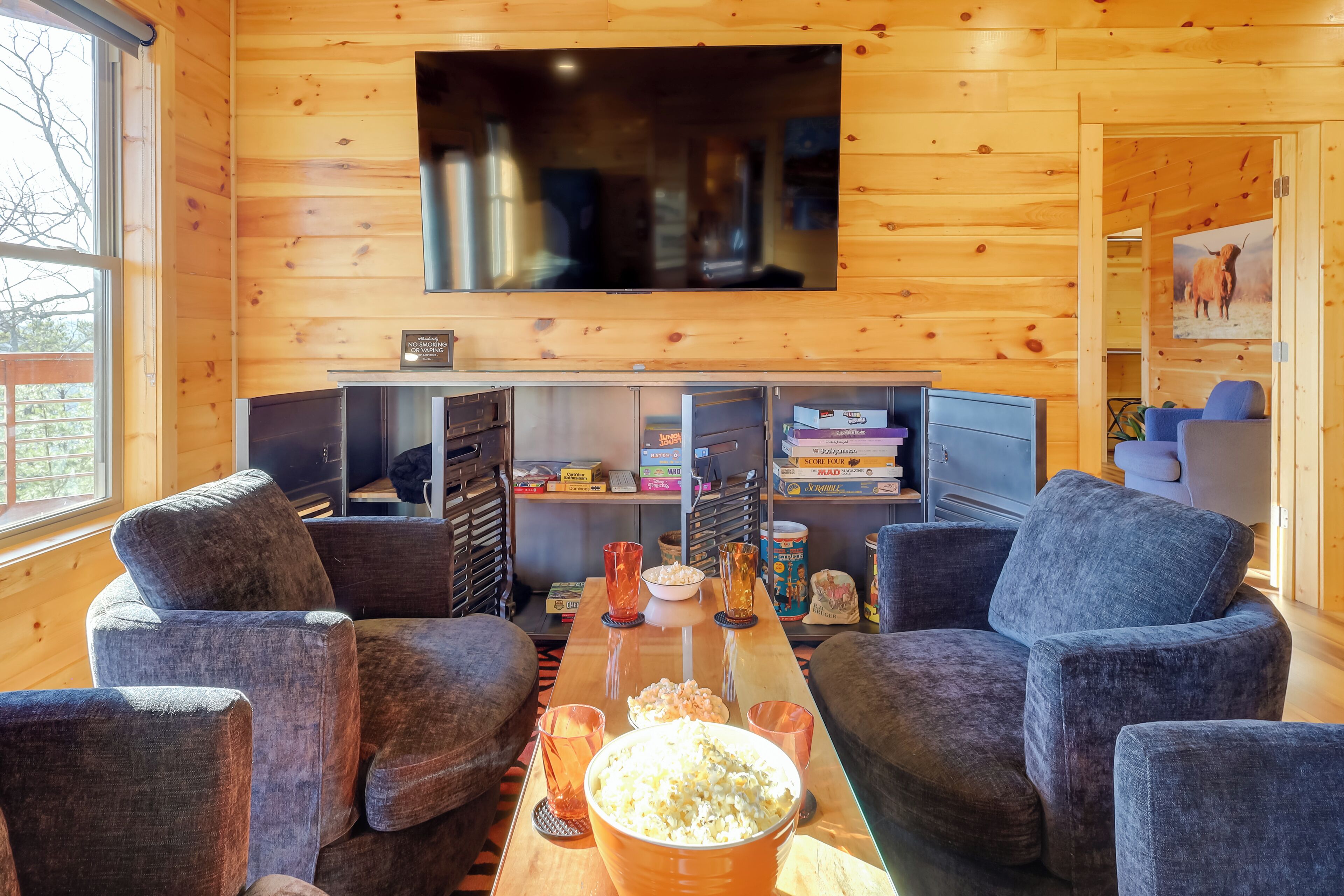 Un soggiorno accogliente con una televisione a schermo piatto montata a parete, posti a sedere comodi e un’ampia ciotola di popcorn sul tavolino.