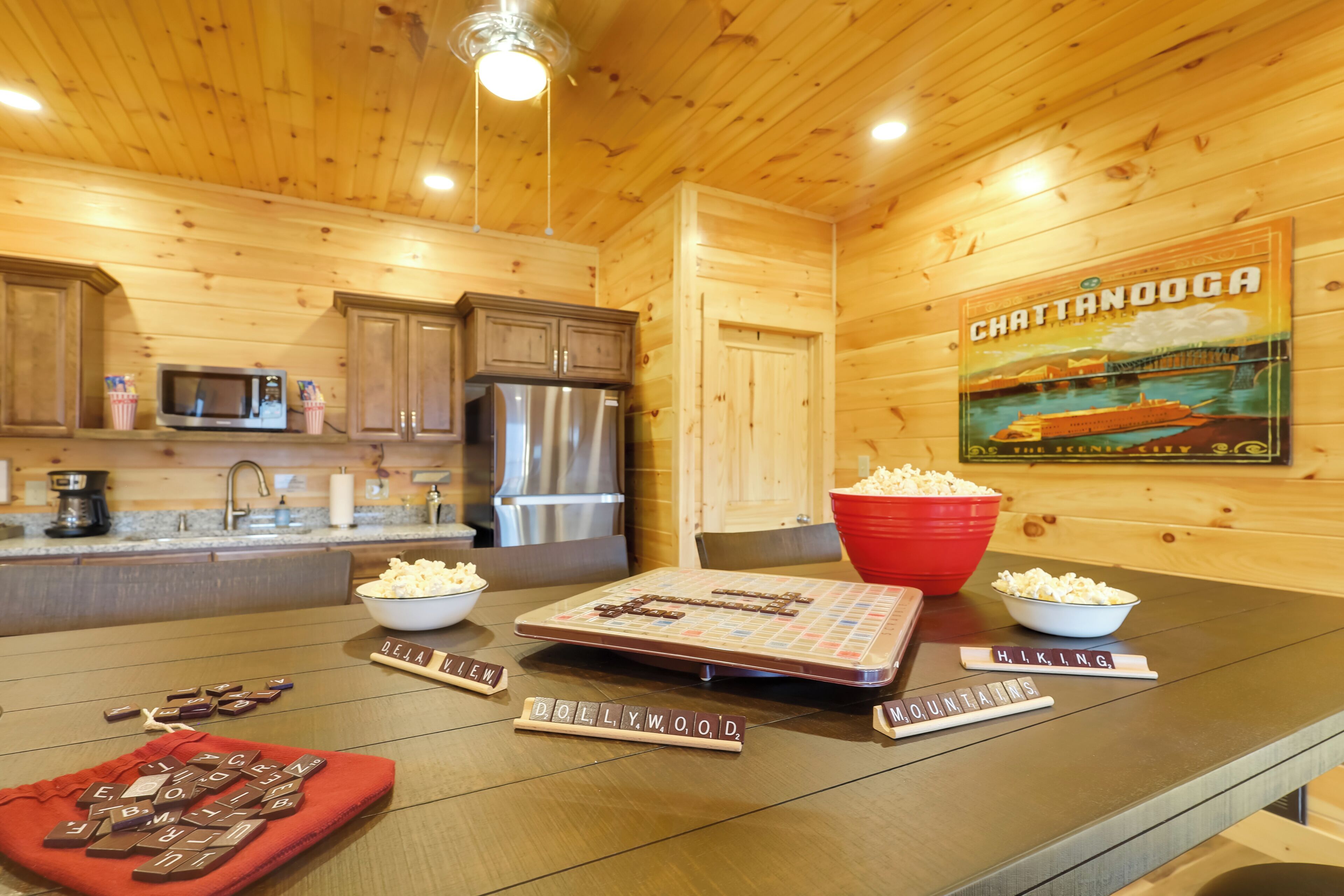 L’intérieur est en bois et comprend un coin cuisine équipé d’un four à micro-ondes, d’un réfrigérateur et de placards en bois. On y trouve une table avec un jeu de Scrabble, des bols de pop-corn et un tissu rouge.