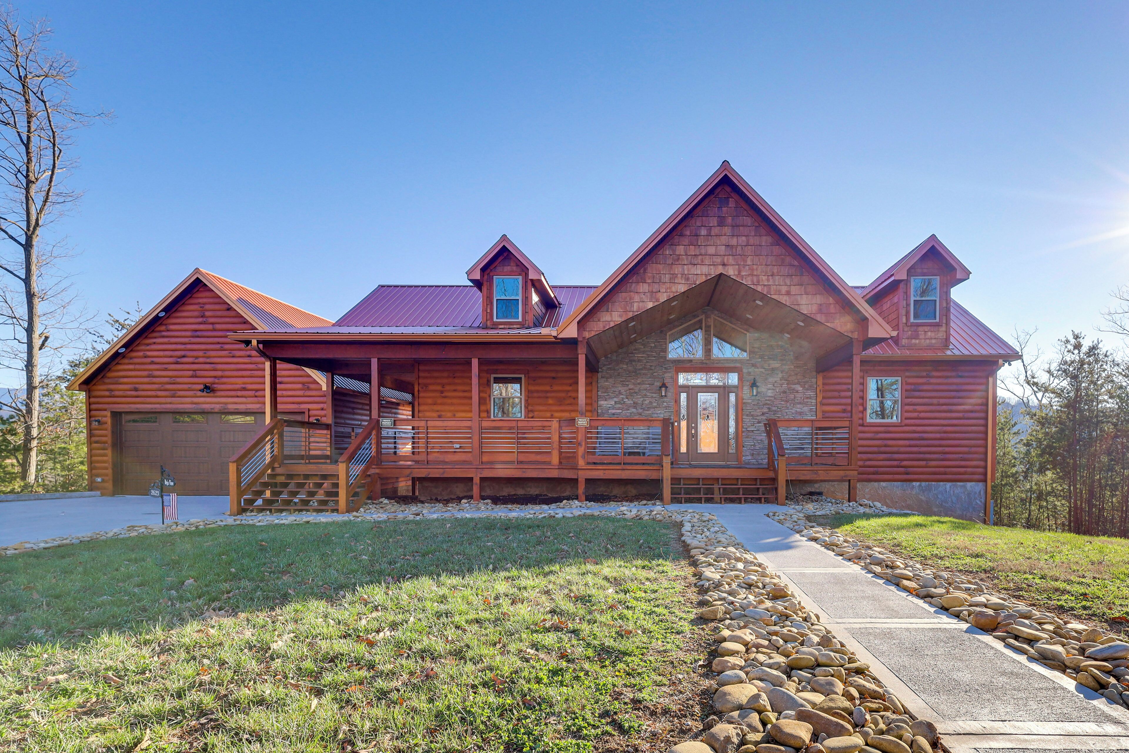 A large log cabin with a stone foundation, multiple windows, and a covered front porch.