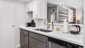 A modern kitchen with white cabinetry, a stainless steel dishwasher, and a coffee maker. - Chill 2BR Near ASU, Pool, Grill, Pkng, Pet Frndly (Tempe)
