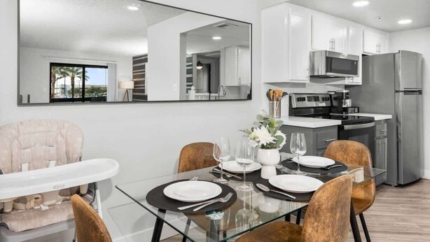 A modern dining area with a glass table, white plates, and a large mirror above. - Chill 2BR Near ASU, Pool, Grill, Pkng, Pet Frndly (Tempe)