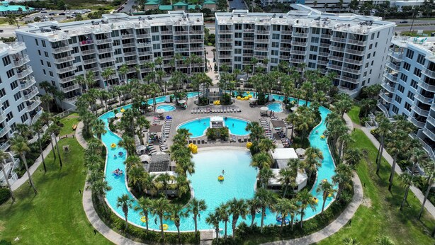 Ein Resort mit mehreren Schwimmbecken, Palmen und Blick auf den Ozean.
