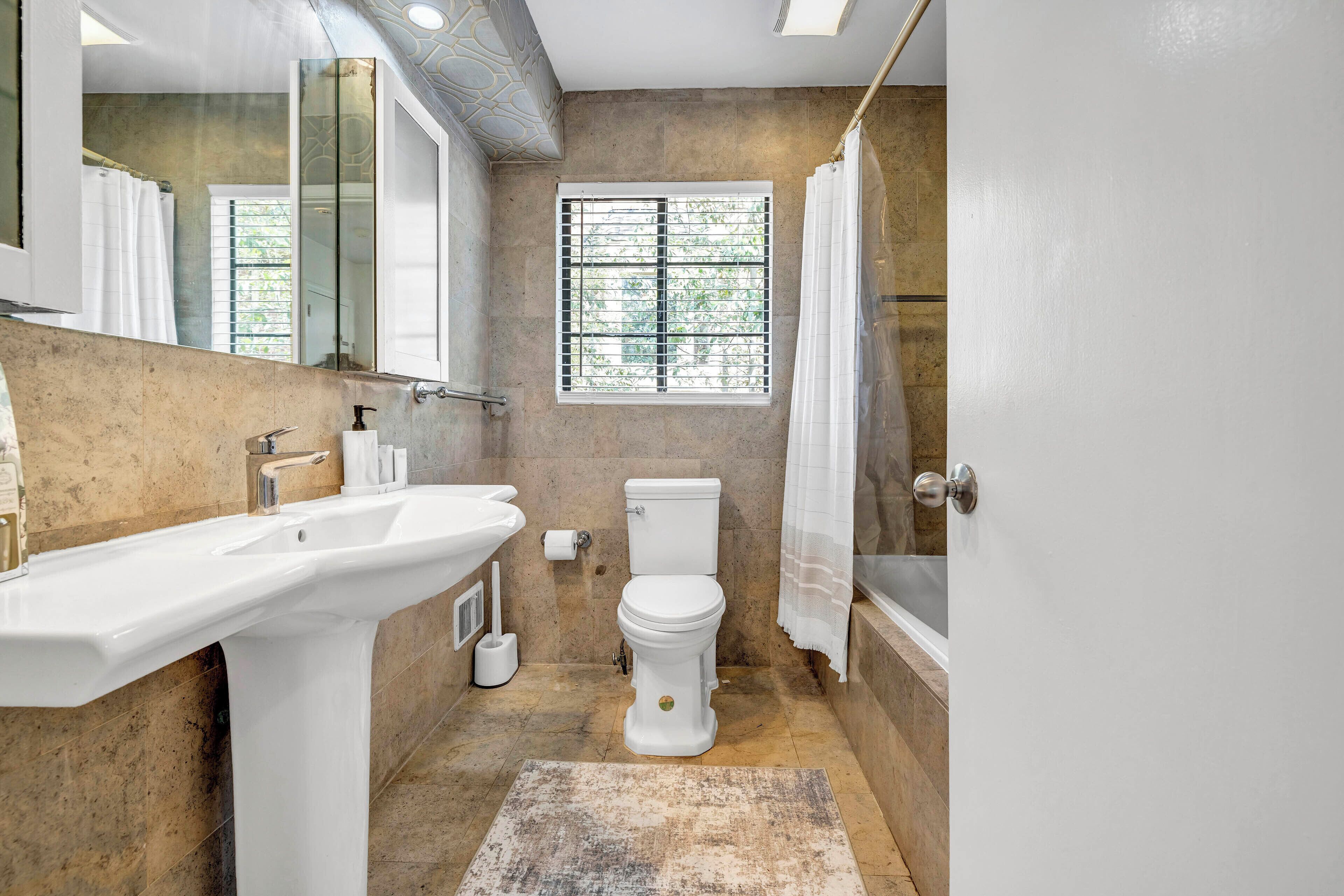 Un baño con lavamanos, inodoro y bañera blancos.