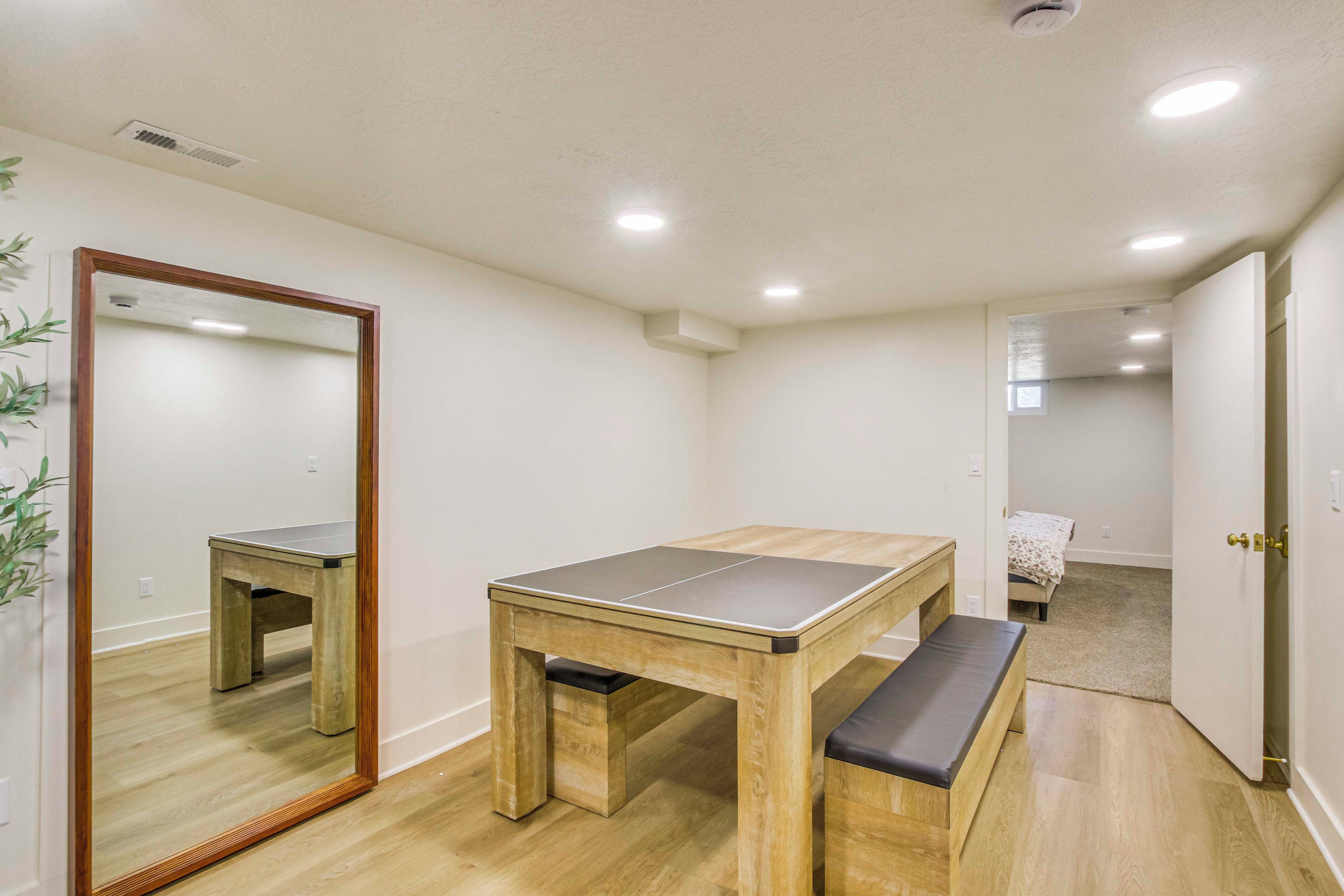 Una habitación con una mesa de madera y un banco, un espejo y una puerta que da a otra estancia.