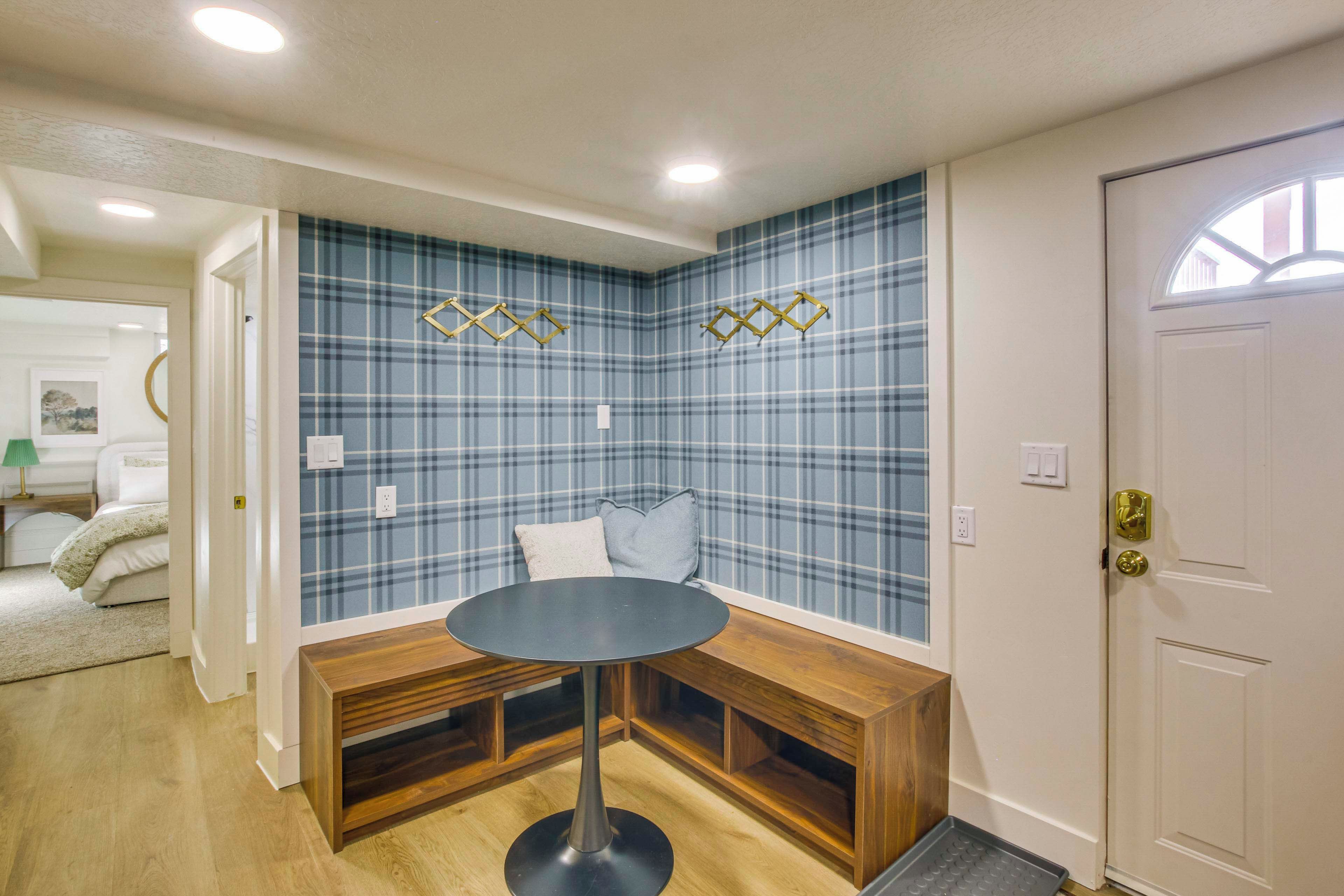 A corner room with a plaid-patterned wall, a round table, and built-in benches.