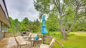 A wooden deck with outdoor furniture, including chairs and a table, and a blue umbrella. - 8 Mi to Crystal Mountain: Peaceful Up North Home (Copemish)