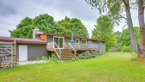 A two-story house with a deck, a chimney, and a covered porch. - 8 Mi to Crystal Mountain: Peaceful Up North Home (Copemish)