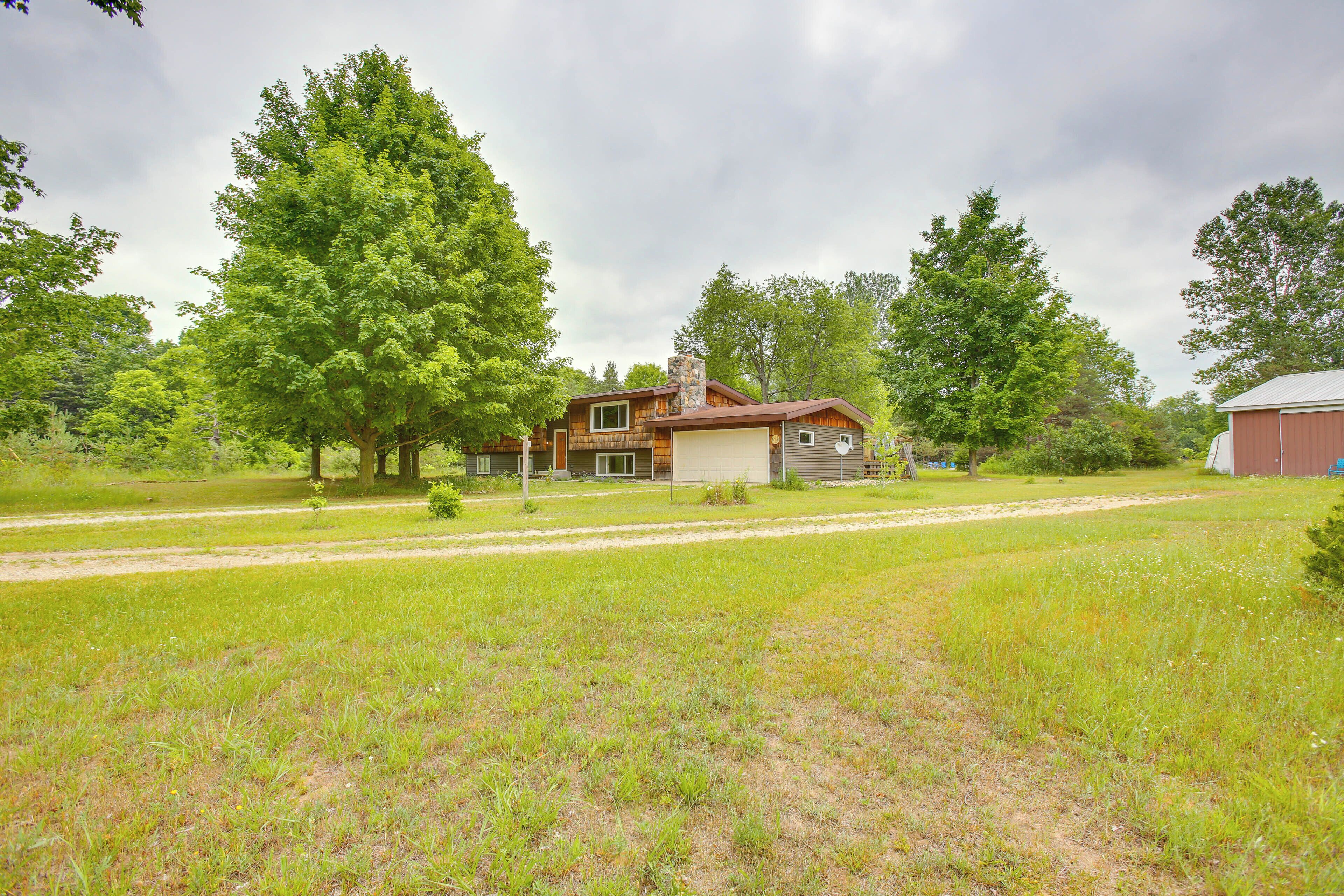 A two-story house with a garage, surrounded by a grassy field and trees.