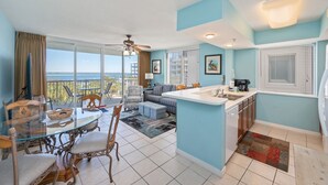 A modern kitchen with a dining area, large windows, and a view of the ocean.
