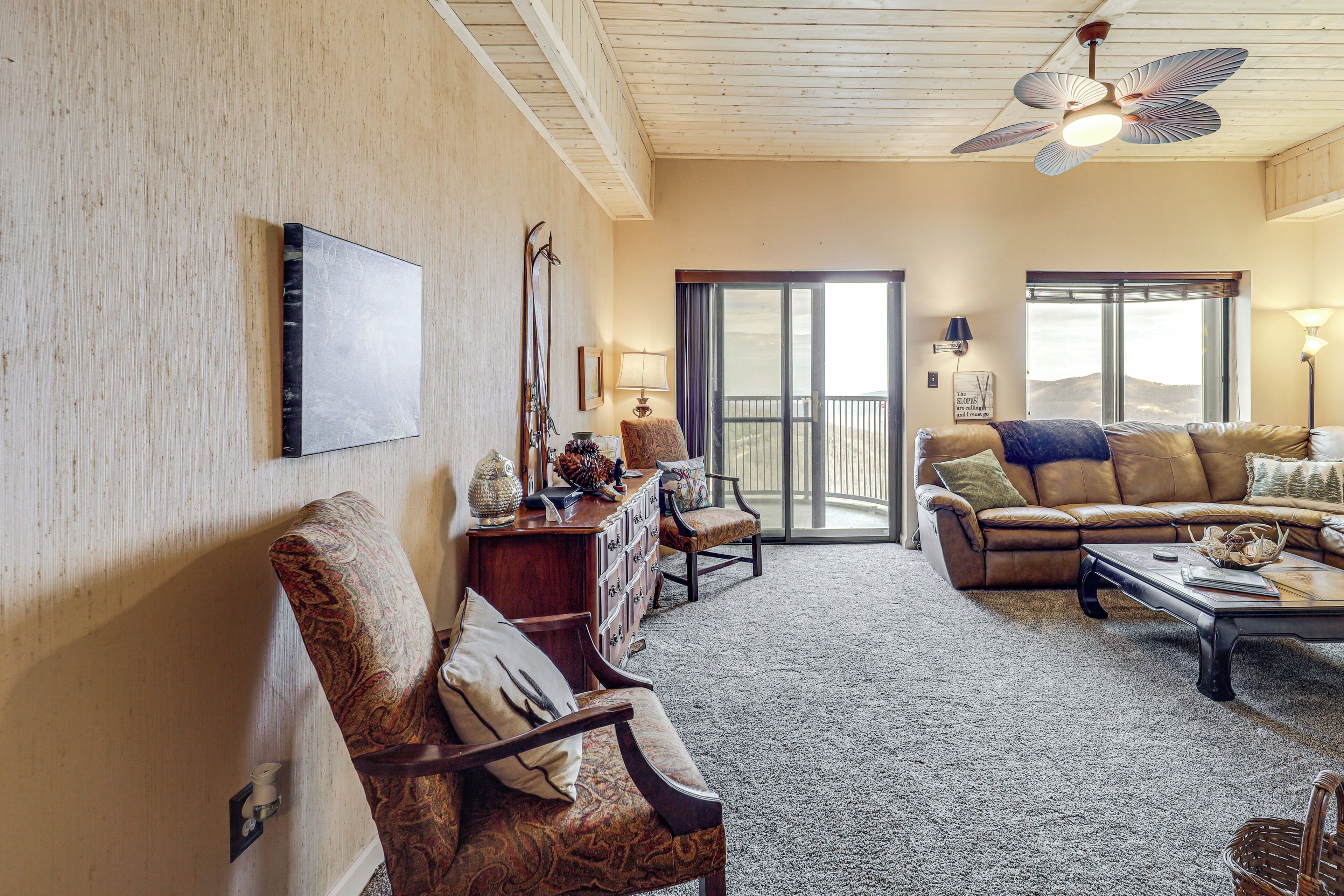 A living room with a sofa, armchair, and a ceiling fan.