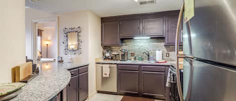 Cocina con encimeras de granito, electrodomésticos de acero inoxidable y armarios de madera oscura.