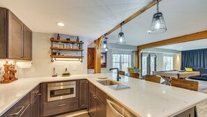 Eine moderne Küche mit Edelstahlgeräten, Holzschränken und einer Marmorarbeitsplatte.